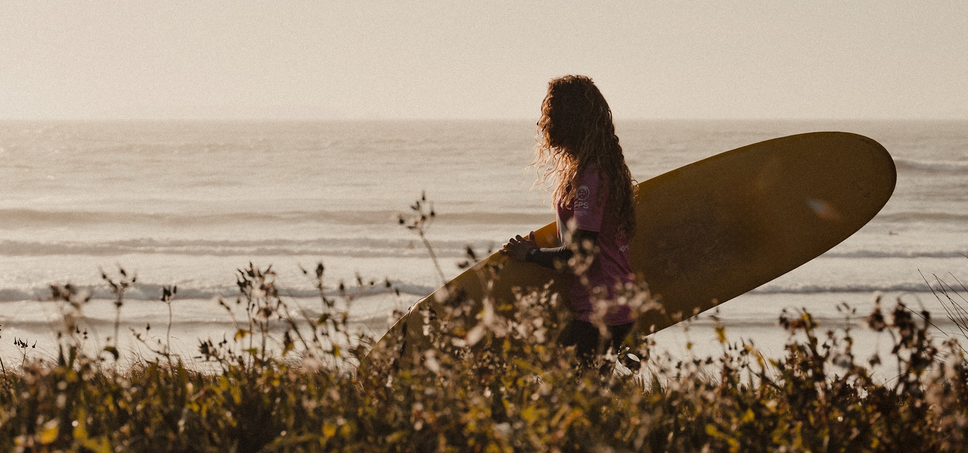 Surfer with longboard at sunset on the Peniche peninsula, Portugal